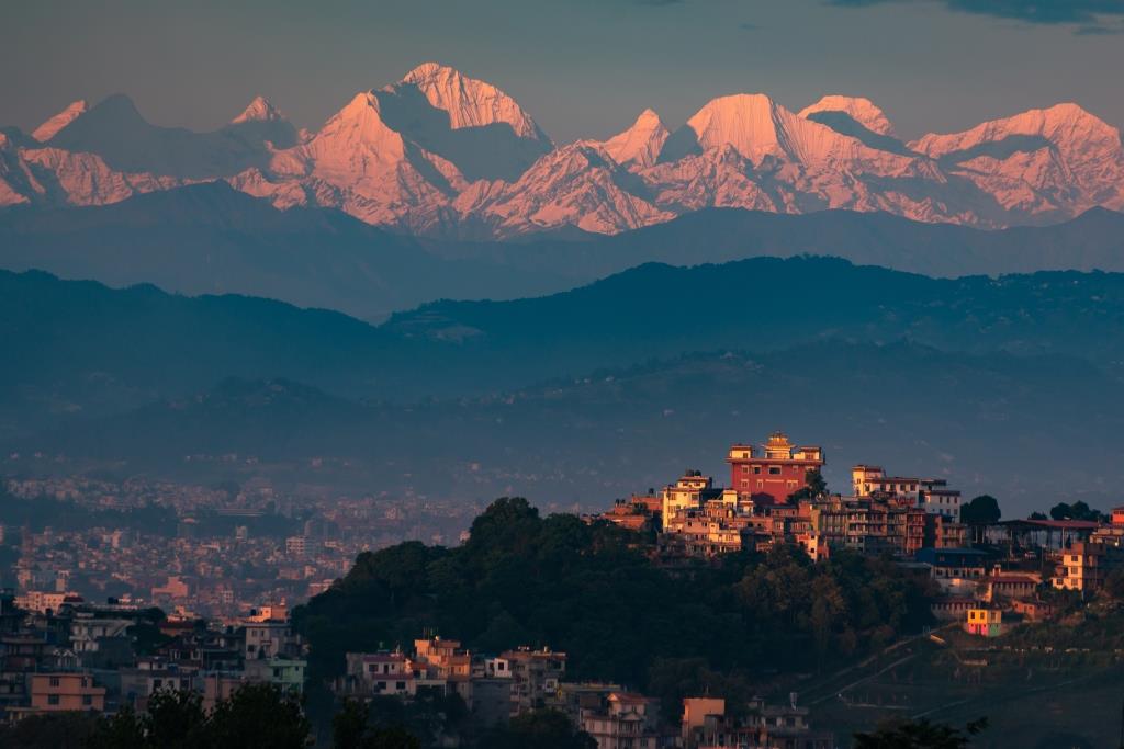 Kathmandu Valley skyline at sunset with the Himalayas rising behind the city